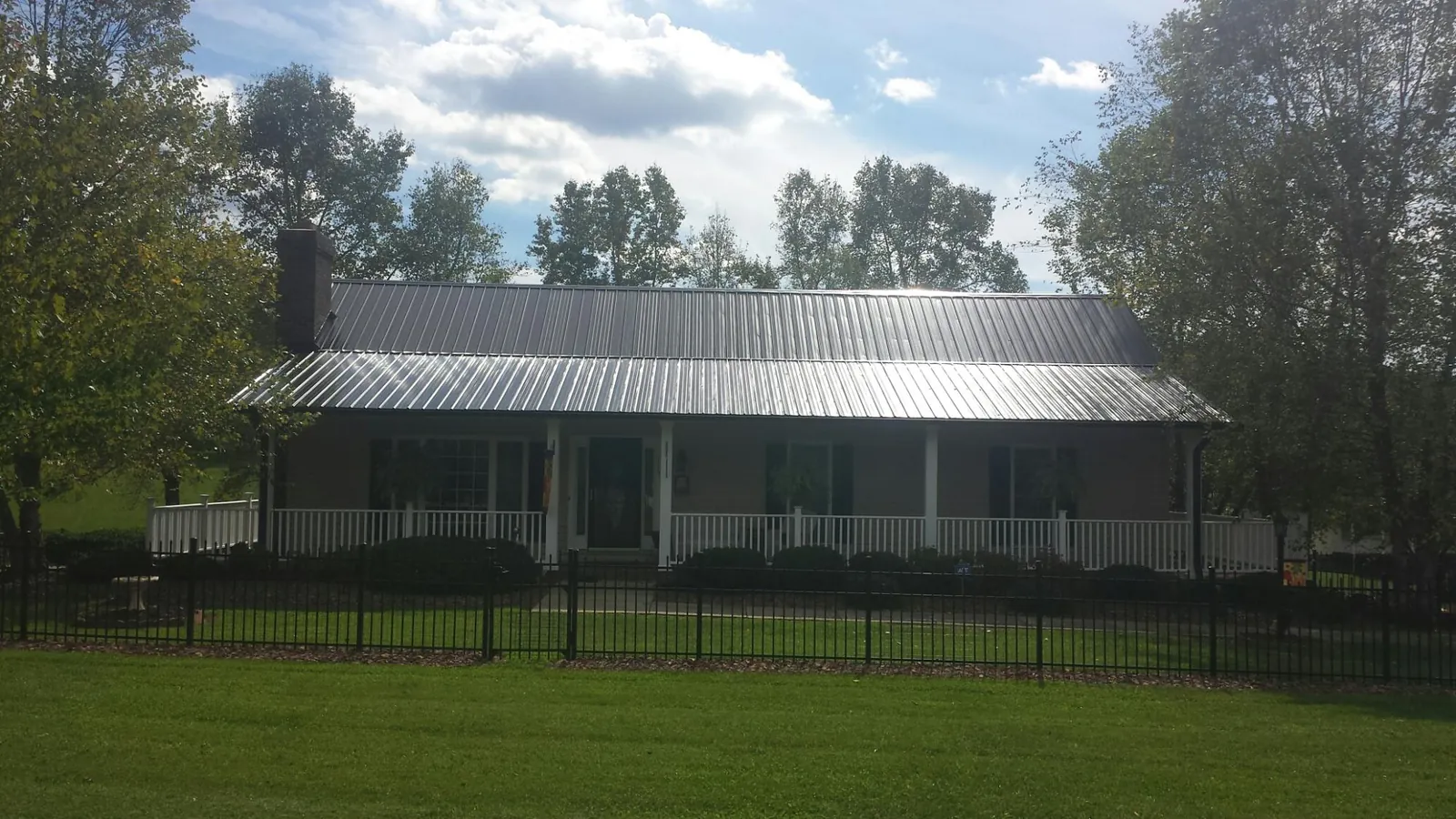 Gray metal roof on a brick ranch with a full width front porch — Gutter Guard Installation work by our crew in Craigsville