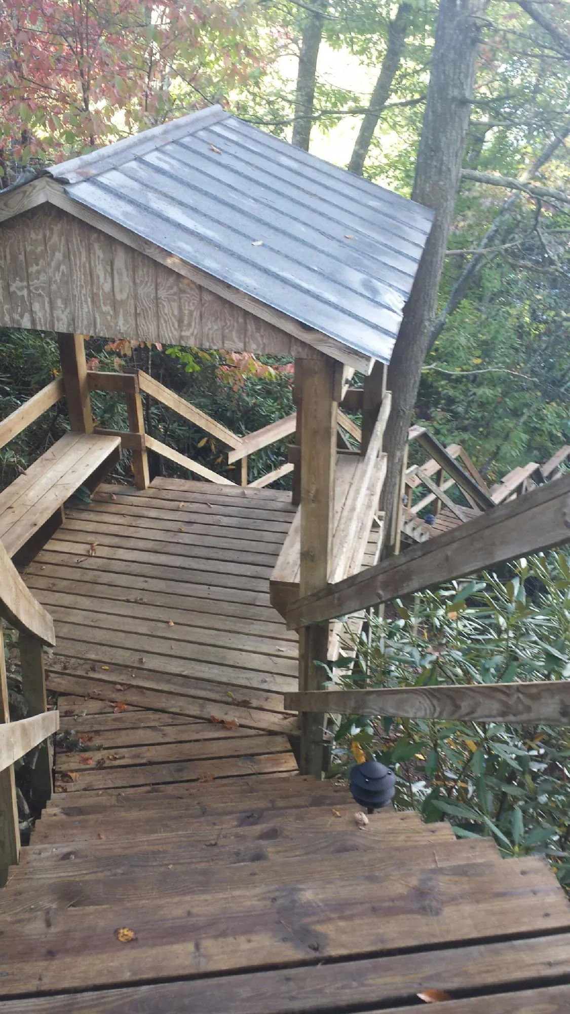 Metal roofed shelter over wooden steps on a wooded walkway — Skylight Repair & Installation work by our crew in Craigsville